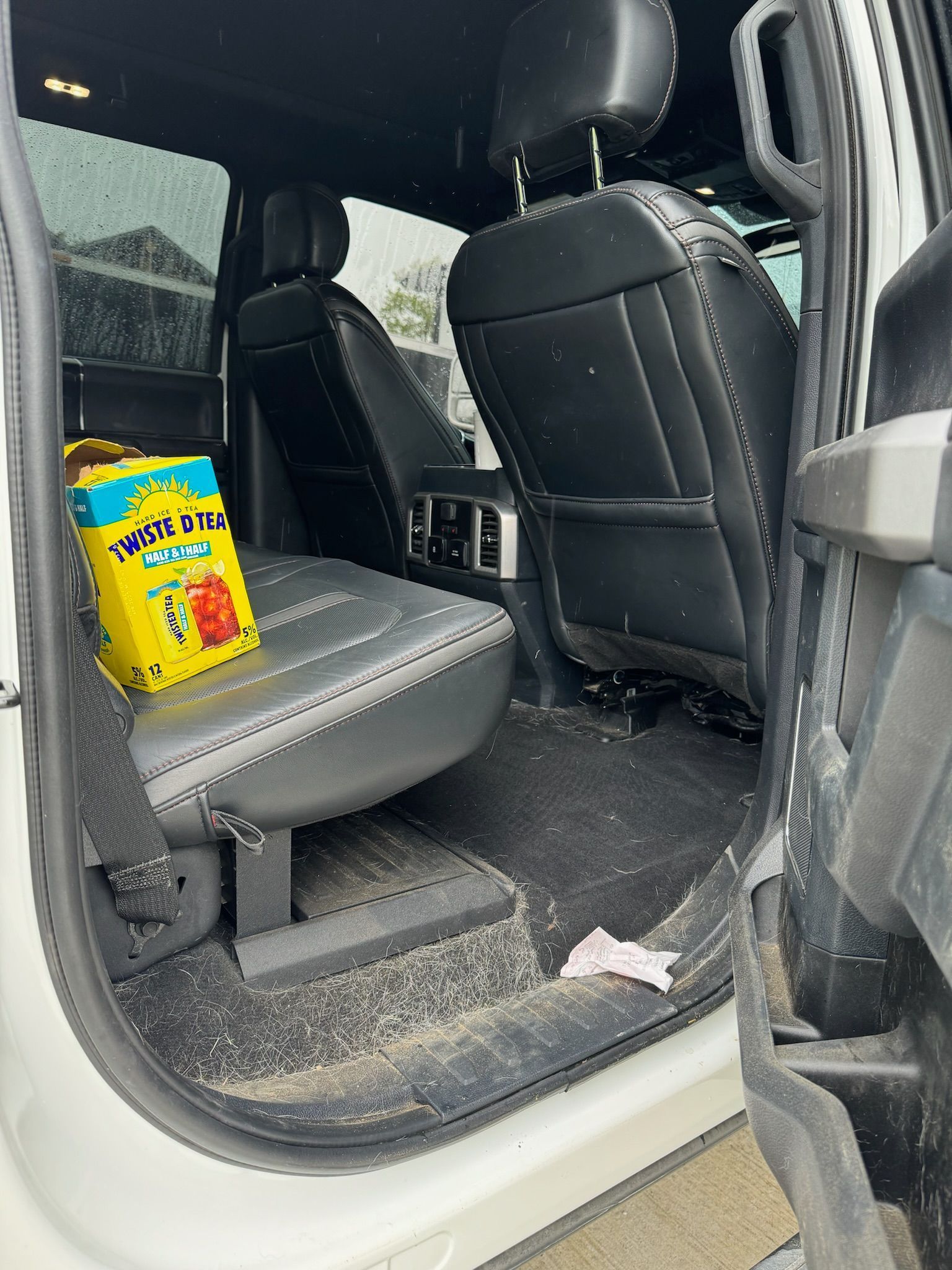The inside of a white truck with a bag of twizzlers in the back seat.