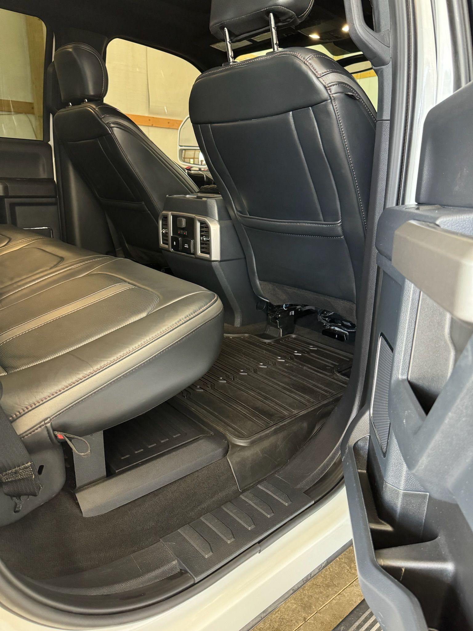 The back seat of a white truck with the door open.