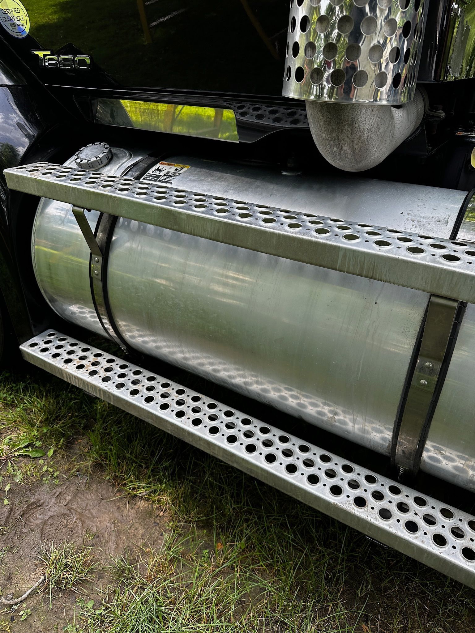 The side of a semi truck with a fuel tank and steps.